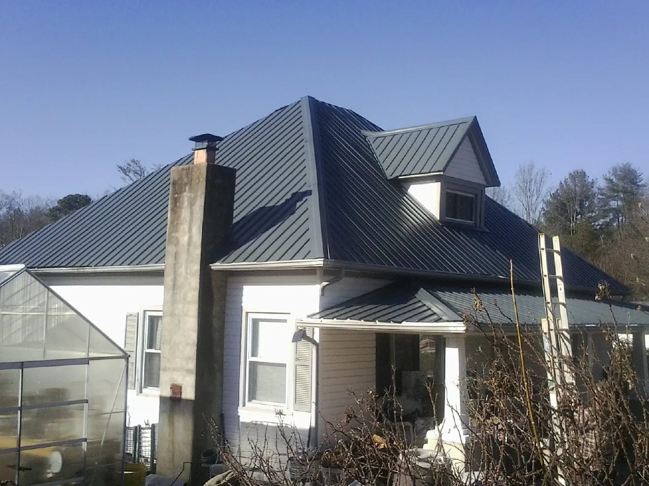 Dark blue standing seam metal roof on a white farmhouse with dormer — Slate & Tile Roof Repair by Roofing Brothers in Mattapan