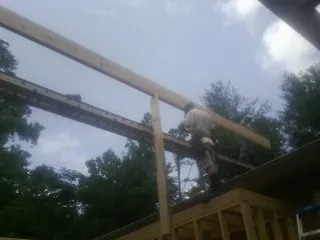 Carpenter setting a ridge beam over a new addition frame — Ice Dam Removal by Roofing Brothers in Mattapan