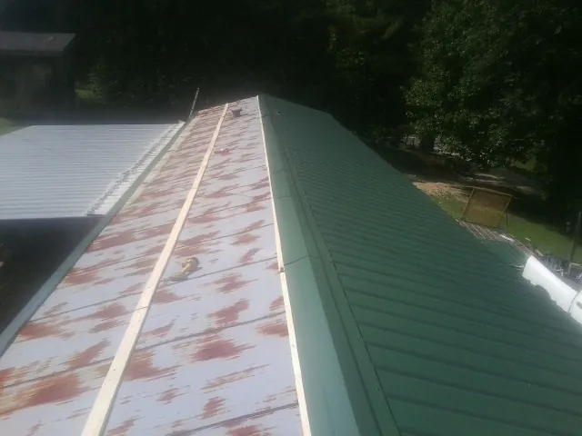 Old rusted panels beside newly installed green metal roofing — Wind Damage Roof Repair by Roofing Brothers in Mattapan