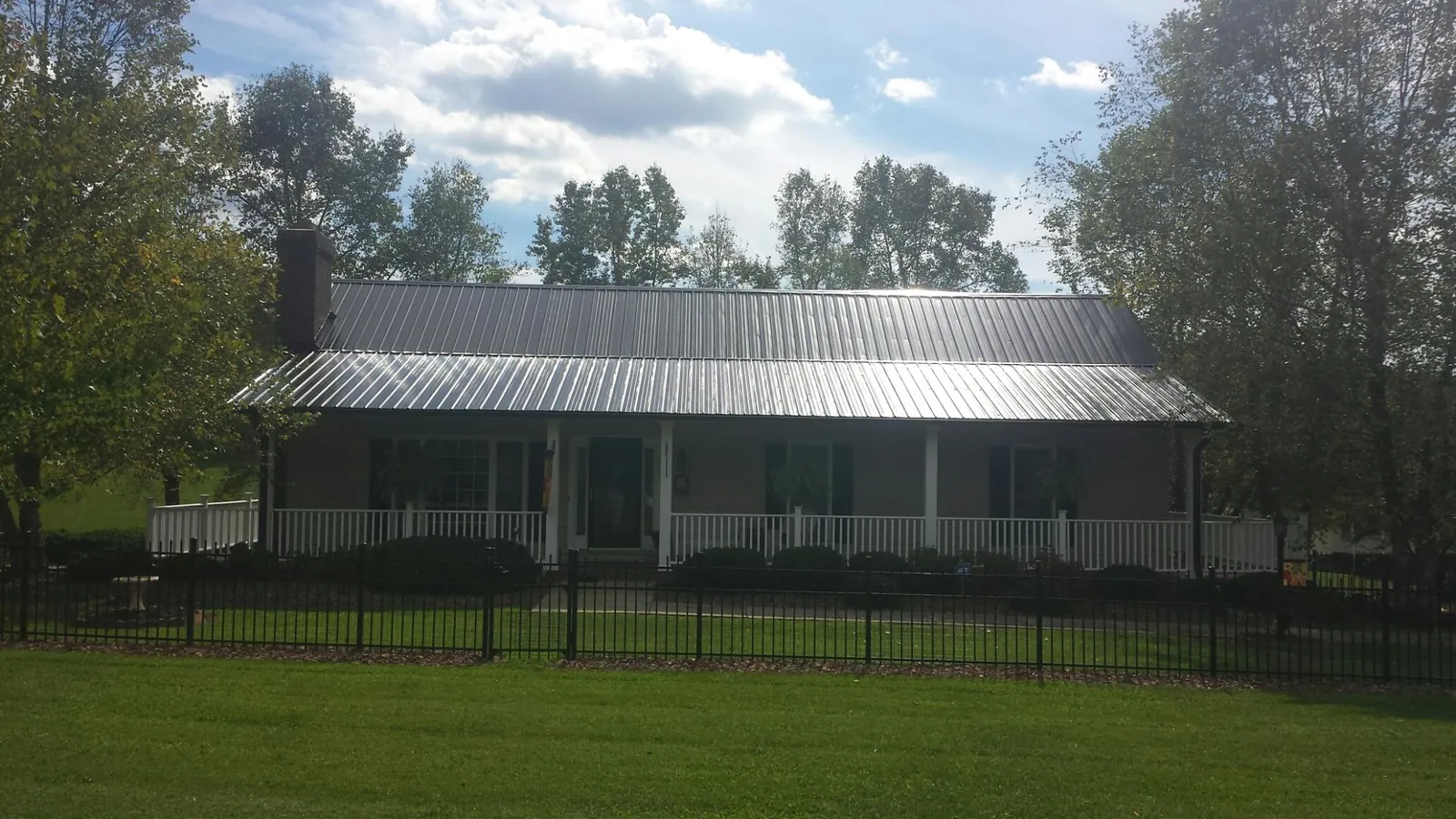 Gray metal roof on a brick ranch with a full width front porch — Gutter Guard Installation work by our crew in Mattapan