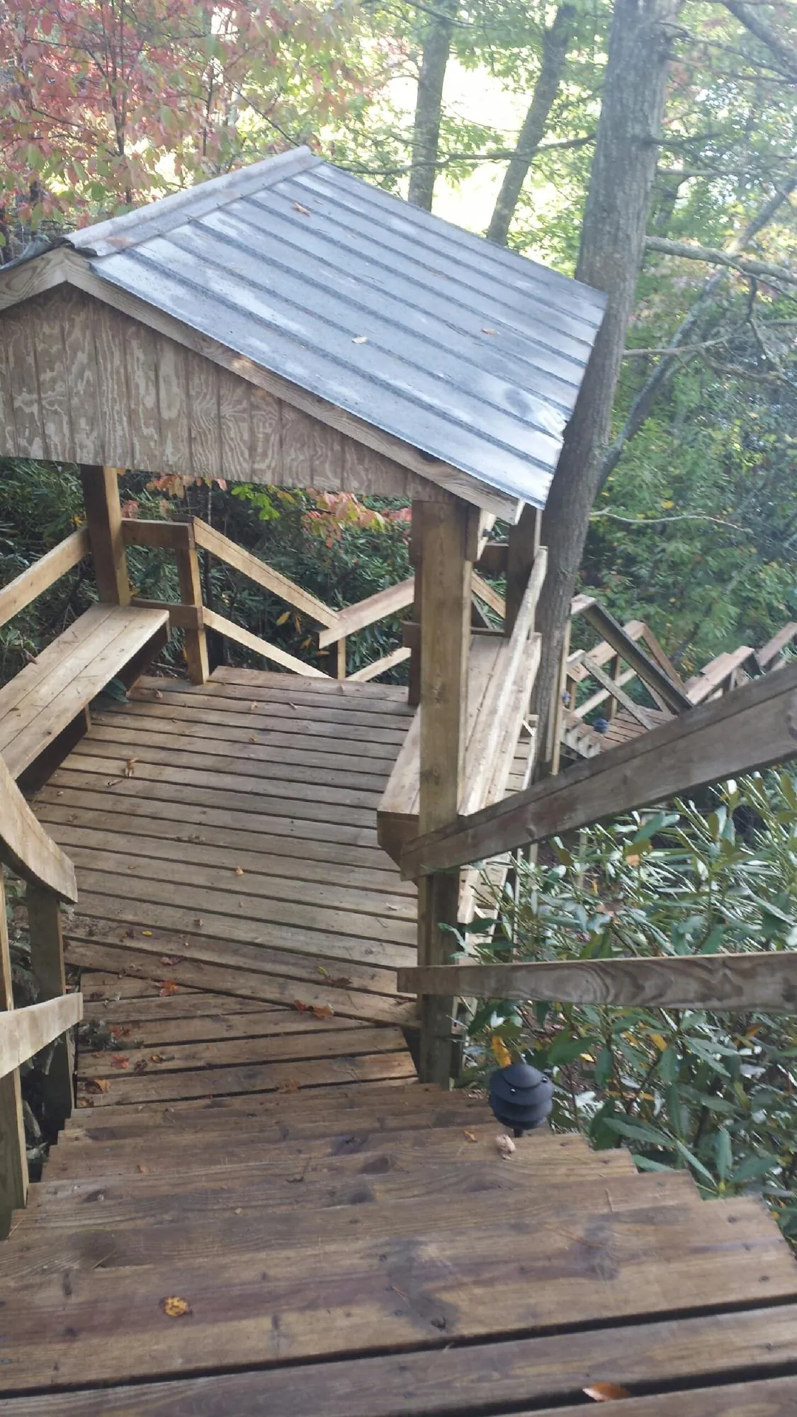 Metal roofed shelter over wooden steps on a wooded walkway — Skylight Repair & Installation work by our crew in Mattapan
