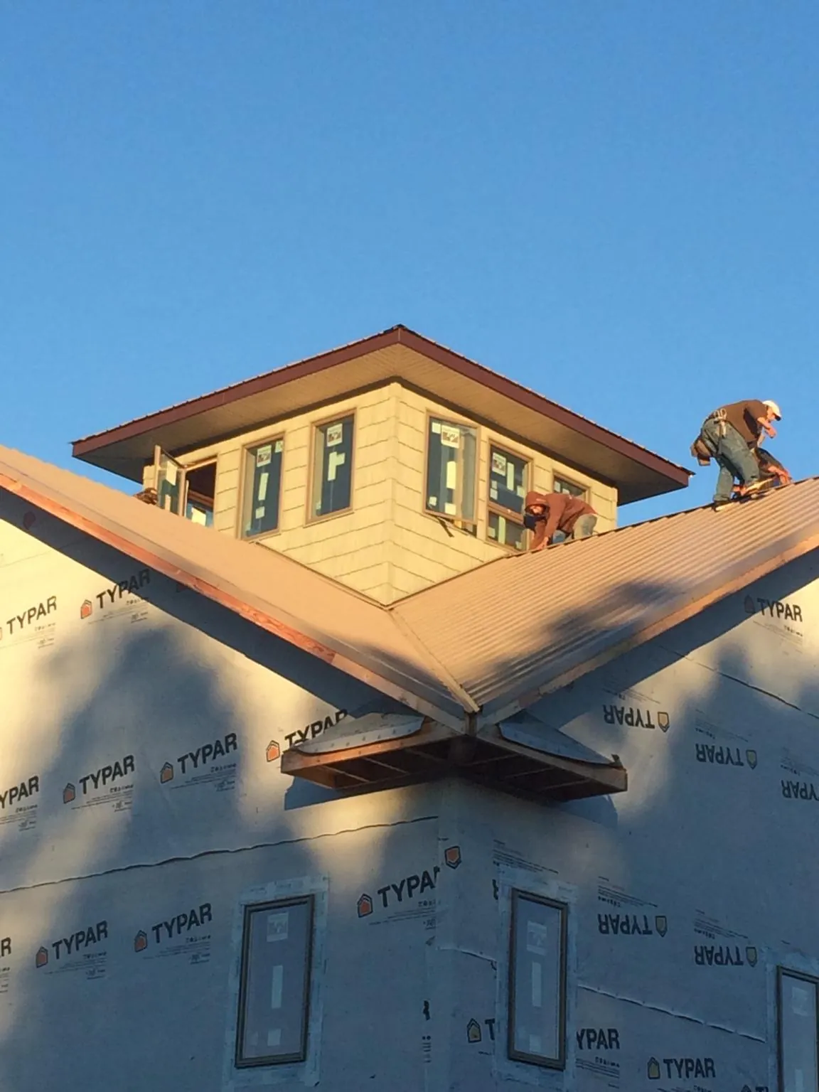 Roofers working around a rooftop cupola on a new metal roof at sunset — Roof Waterproofing in Mattapan by Roofing Brothers